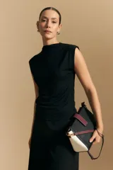 Top sin mangas negro, con cuello alto y hombros ligeramente estructurados. El tejido presenta una textura sutil con brillo integrado que simula un animal print.