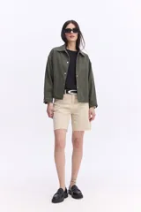 Short de jean tiro alto, corte recto y largo intermedio, de color beige con ruedos desflecados y lavado desgastado.