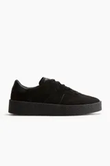 Zapatillas deportivas negras de gamuza con cuello acolchado, lengüeta, cierre de cordones y suela texturizada gruesa.