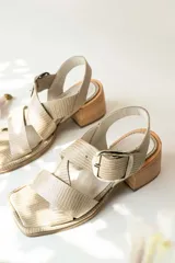 Sandalias de cuero negro con textura de reptil, diseño de punta cuadrada y taco bloque de madera. Presentan tiras cruzadas en el empeine y una hebilla metálica grande decorativa.