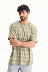 Remera oversize de manga corta confeccionada en 100% algodón, con diseño a rayas horizontales en tonos verde y blanco.