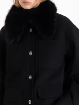 Chaqueta de paño color negro con cuello desmontable de piel sintética, bolsillos plaqué frontales y cierre con botones metálicos.