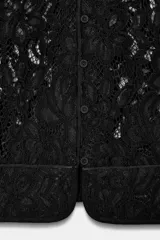 Blazer de encaje negro con hilatura de algodón, cuello redondo, manga larga y cierre frontal de botones.