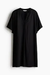 Vestido túnica de viscosa color negro, de corte holgado, largo hasta la rodilla, con cuello mao y abertura en V. Cuenta con mangas cortas, hombros caídos y aberturas laterales en el bajo.