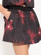 Mini falda negra con estampado de flores rojas, cintura elastizada y bolsillos laterales.
