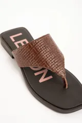 Sandalias de cuero color marrón, tipo ojota con taco bajo, tira ancha con textura trenzada y plantilla con inscripción de la marca.