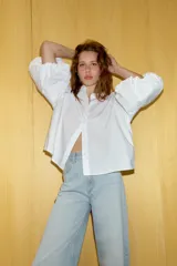 Camisa de algodón con cuello solapa y cierre frontal con botones ocultos. Presenta mangas abullonadas por debajo del codo con terminación elástica.