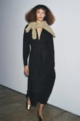 Vestido midi negro de algodón, con escote pico pronunciado, manga larga con puños y detalle de pliegues en el torso. Incluye un cinturón ajustable del mismo tejido anudado a la cintura.