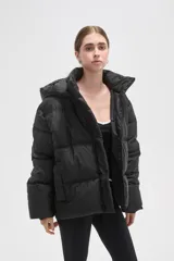 Campera puffer color beige con diseño capitoneado, capucha integrada y cierre frontal oculto. Presenta bolsillos laterales y un corte holgado.