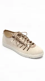 Zapatilla casual de cuero color beige claro con detalles metalizados en tono dorado y recortes laterales. Cuenta con cordones finos metalizados y suela baja de goma blanca.