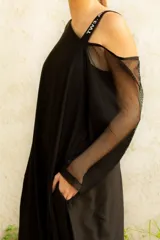 Vestido negro irregular con un solo tirante ancho con letras blancas y bolsillos laterales.