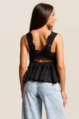 Conjunto de dos piezas color blanco, compuesto por una musculosa con escote en V con detalles de encaje y volados en el torso, y un short a juego con terminaciones de encaje calado en el ruedo.