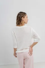 Buzo de tejido abierto color beige claro, de calce oversize con mangas 3/4 y cuello redondo. Presenta terminaciones acanaladas en puños y cintura.