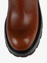 Bota de cuero color marrón con caña alta, hebillas decorativas y suela track.