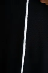 Pantalón negro de corte ancho con dos líneas blancas verticales en los laterales.