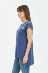 Remera de algodón negra, de corte holgado, con cuello redondo a la base y detalle de estampado floral en el hombro izquierdo.