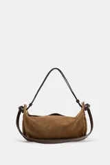 Bolso de mano formato alargado confeccionado en piel, con doble asa, una de mano y otra de hombro, con detalle de nudos y ojales metálicos. Cuenta con cierre mediante solapa y cremallera, y bolsillo interior con cremallera.