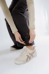 Pantalón de jean negro de corte recto y tiro alto, con detalle de botones en el dobladillo de la pierna.