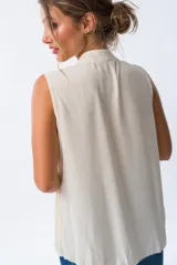 Blusa blanca sin mangas con cuello mao y pliegues verticales.