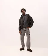 Pantalón de jean corte baggy con diseño holgado y tiro alto. Presenta bolsillos laterales funcionales tipo cargo en los muslos, cierre frontal con botón y cremallera, y trabillas en la cintura.