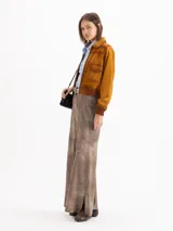 Campera bomber confeccionada en gamuza color tostado, con cierre frontal, bolsillos aplicados con solapa en el pecho y puños y cintura tejidos en marrón oscuro.
