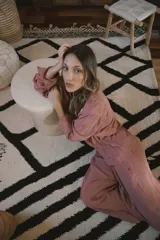 Camisa de lino negra con bordados dorados en forma de árbol o palmera estilizada. Presenta cuello camisero, botones frontales dorados y pliegues verticales en la parte inferior delantera.