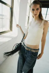 Top corsetero de color marfil confeccionado en tejido elástico, con escote redondo, tirantes anchos y costuras marcadas que estructuran la prenda.