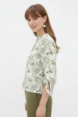 Blusa estampada de viscosa con diseño abstracto en tonos beige, negro y marrón, escote en V con cuello mao y mangas tres cuartos con detalles de lazos en los puños.