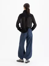 Jeans de mezclilla azul oscuro, modelo balloon con tiro alto, pierna muy ancha y puños ajustables con botón en el tobillo para crear volumen.