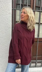 Polera de tejido de punto con diseño de ochos, color bordó, de corte oversize y cuello alto, con puños y ruedo acanalados.
