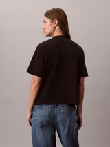 Remera Calvin Klein de manga corta y cuello redondo, color negro, con logo de la marca bordado en 3D en tono verde en el pecho. Presenta un corte regular y mangas con vuelta.