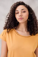 Remera negra de algodón peinado, ajustada al cuerpo, con cuello redondo y detalles de vainillas caladas en el escote y los hombros. Las mangas son cortas y están dobladas hacia afuera.