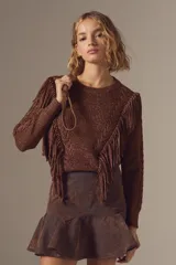 Sweater de tejido de punto con lurex color marrón, diseño con flecos frontales y detalles de trenzas en las mangas. Presenta cuello redondo y corte ajustado.