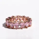 Anillo de acero con acabado en oro rosa, con cristales rosas en forma de corazón engarzados en diseño infinito.