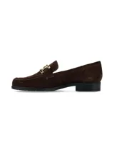 Mocasín de gamuza color marrón oscuro, con detalle de herraje metálico dorado en el empeine y suela plana de goma negra.