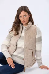 Chaleco de sherpa color beige con cierre frontal, cuello alto y bolsillos laterales con detalles en cuero sintético.