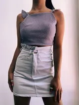 Crop top negro con textura brillante, breteles anchos con volados y espalda descubierta que se ata con lazos.