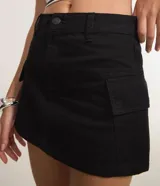 Pollera corta de sarga color negro, con diseño de tiro alto, cierre frontal con botón y cremallera, pasantes para cinturón y bolsillos cargo laterales.