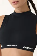 Top deportivo negro con cuello alto, sin mangas y logo retro BASSET 2001 estampado en el frente.