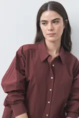 Camisa de manga larga de algodón en color blanco, con cuello clásico, cierre frontal de botones y silueta relajada.