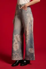 Pantalón jean de tiro medio y corte ancho, con estampado artístico en tonos celestes y blancos.