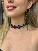 Aros largos con base circular dorada de bronce y múltiples tiras colgantes de strass en color verde. Presentan un diseño llamativo con un largo total aproximado de 12 cm.