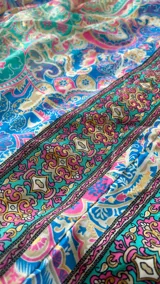 Vestido largo estampado con diseño paisley en tonos azules, verdes y rosados. Presenta un escote halter y un corte holgado que cae hasta el tobillo.