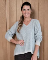 Sweater de lana lambswool con cuello en V, diseño holgado y mangas largas con puños acanalados en contraste. Presenta un ruedo asimétrico con detalle de ribete acanalado en color crema.