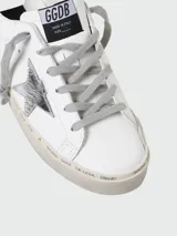 Championes Golden Goose modelo Hi Star, de cuero blanco con estrella plateada y detalles plateados en el talón. Suela alta con inscripciones. Cordones grises.