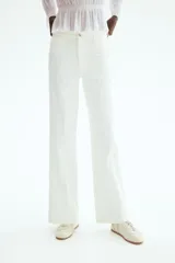 Pantalón jean de tiro alto en color blanco, con diseño de pernera recta holgada, trabillas para cinturón y cierre frontal con botón metálico. Presenta pliegues marcados al frente y bolsillos laterales.