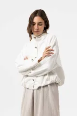 Campera de denim liviano oversize color blanco, con cuello alto, cierre frontal con botones y bolsillos delanteros con solapa. Presenta pespuntes en contraste y una silueta relajada.