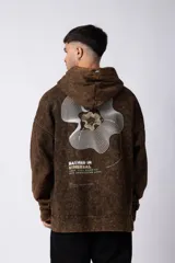 Buzo canguro con capucha, de calce oversize y efecto de lavado ácido en tono marrón. Presenta un bolsillo frontal tipo canguro y un pequeño estampado minimalista en el pecho.