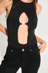 Body negro de seda fría con escote cerrado y abertura en el delantero unida por un aplique metálico con el logo de la marca.
