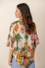 Camisa oversize de lino color crudo, con cuello camisero y estampado multicolor de paisajes tropicales con palmeras y arquitectura.